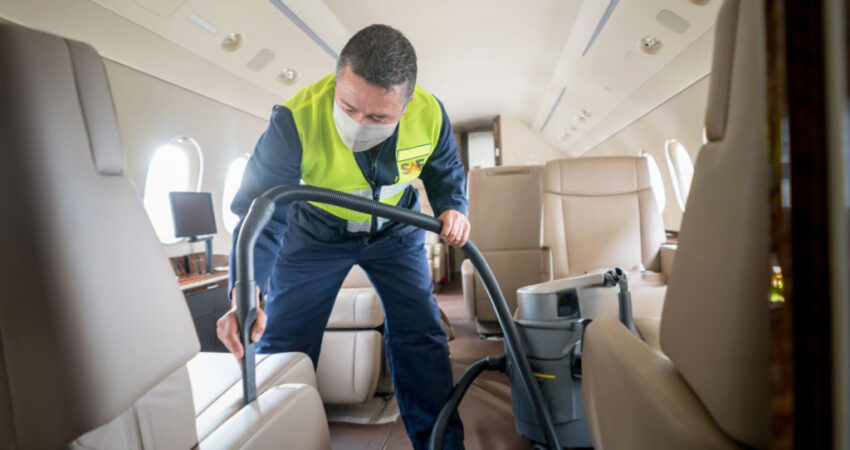 Man cleaning an airplane with a vacuum cleaner and wearing a facemask during the COVID-19 pandemic â aerospace industry