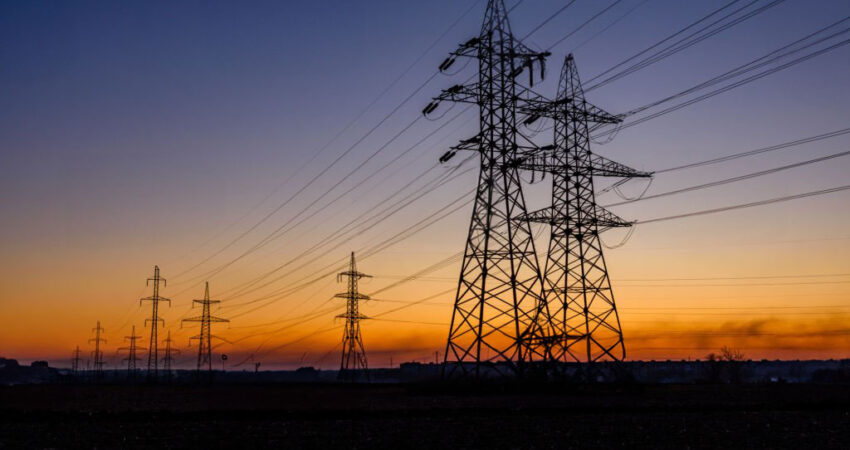 High voltage power line in field at sunset