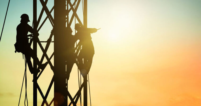 Silhouette electrician work on high ground heavy industry concept. Construction of the extension of high voltage in high voltage stations safely and systematically over blurred natural background.