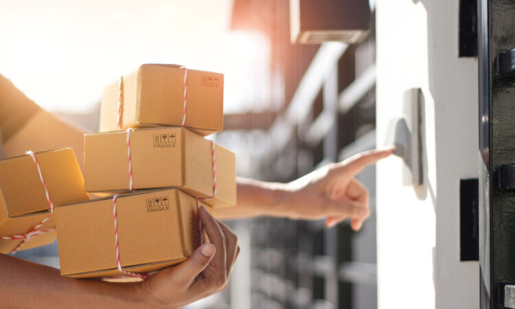 Delivery man holding parcel boxes and ring the doorbell on the client's door in the morning background.