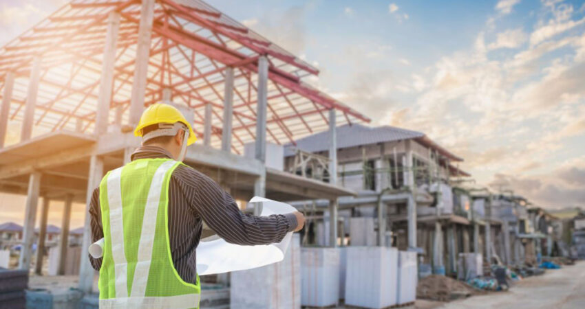 Professional engineer architect worker with protective helmet and blueprints paper at house building construction site background